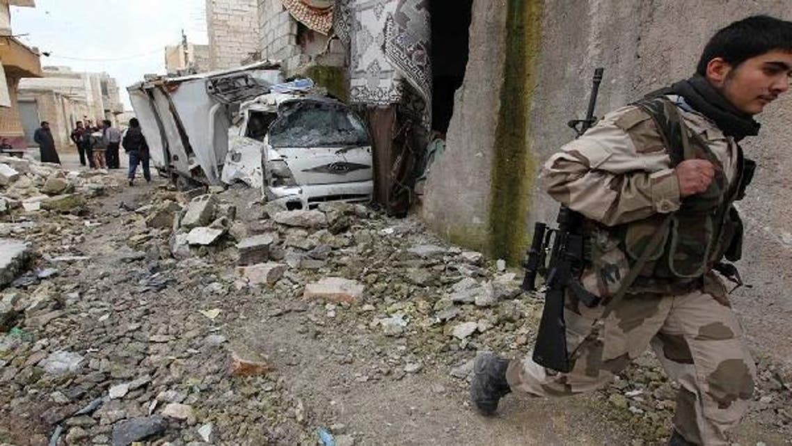 A member of the Free Syrian Army walks past a damaged car in Karm al-Tarab neighborhood in Aleppo Jan.22, 2013. (Reuters)