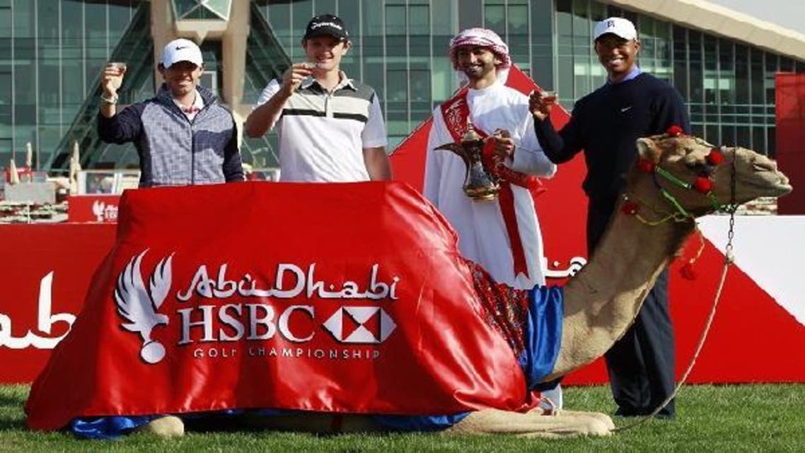 Tiger Woods (R), Justin Rose of England (2L) and world number one golfer Rory McIlroy of Northern Ireland (L) pose with an Emirati man (2R) behind a camel during 20th Abu Dhabi Golf Championship at the Abu Dhabi Golf Club on Jan. 15, 2013. (AFP)