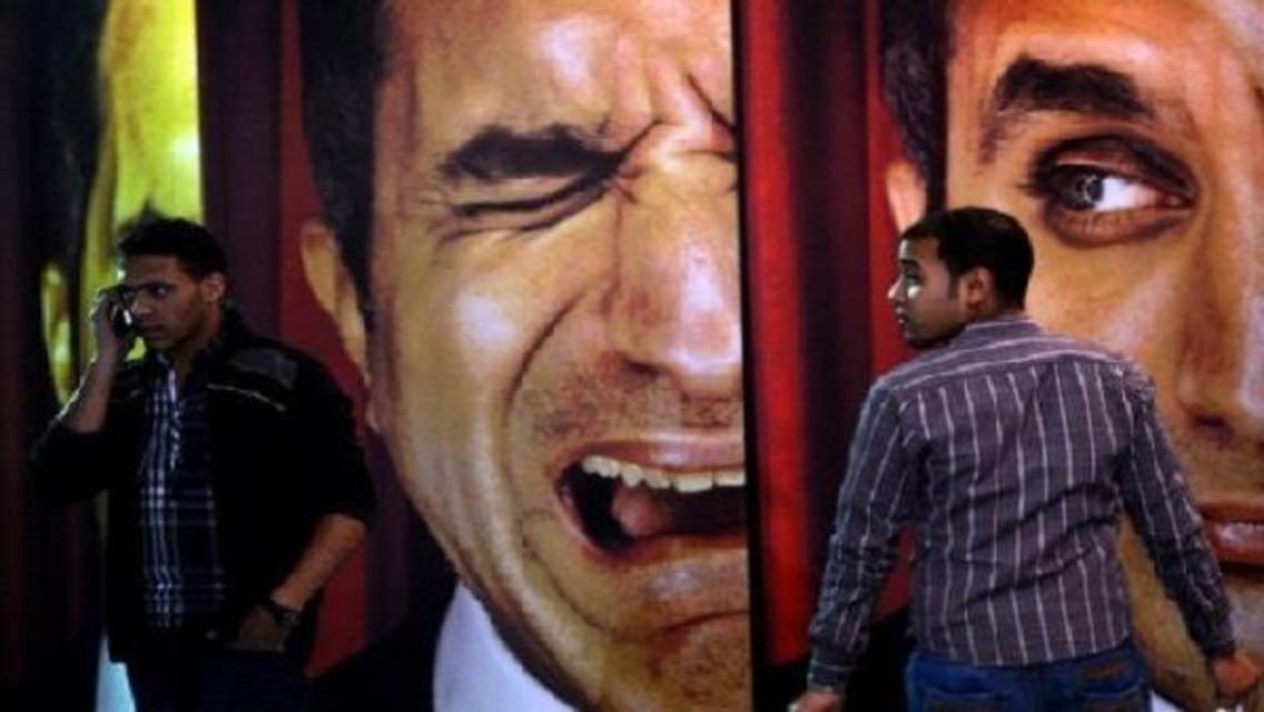 Egyptians walk past posters of Egyptian satirist Bassem Youssef outside a theatre in Cairo on Jan. 22, 2013. The Cairo cafe is packed with patrons in stitches as Youssef fires his caustic criticism at President Mohamed Mursi, but post-revolution media freedoms have proved no laughing matter for some. (AFP)