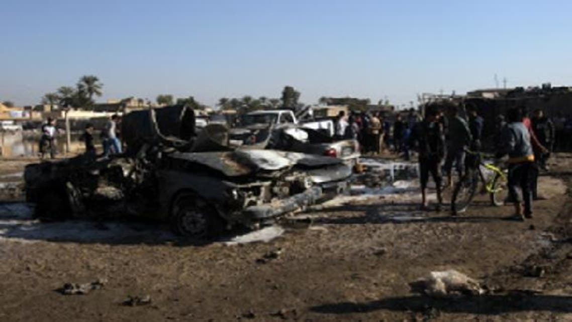 People gather around the site of a car bombing in the north Baghdad neighborhood of Shuala, on Jan. 22, 2013. (AFP)
