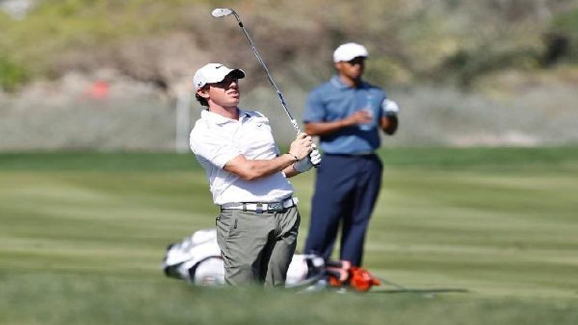 Rory McIlroy of Northern Ireland watches his shot as Tiger Woods of the U.S. drinks water at the third hole during the second round of the Abu Dhabi Golf Championship at the Abu Dhabi Golf Club Jan. 18, 2013. (Reuters)