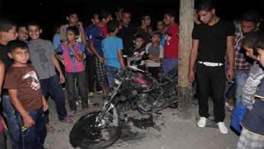 فلسطینی شہری اسرائیلی میزائل حملے کا نشانہ بننے والے موٹر سائیکل کا ڈھانچہ دیکھ رہے ہیں