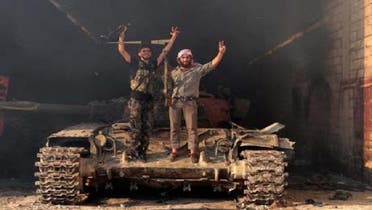 جیش الحر کے دو رکن شامی فوج سے چھینے گئے ایک ٹینک پر فتح کا نشان بنائے کھڑے ہیں۔