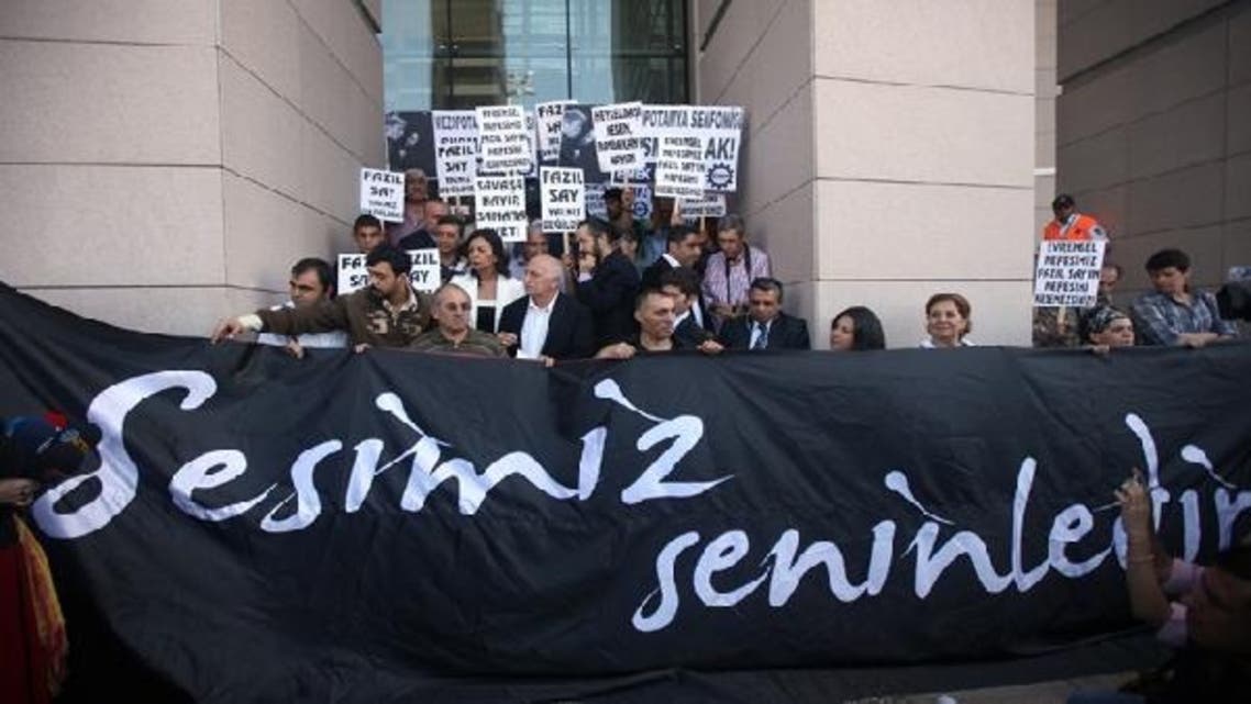 Supporters of world-renowned Turkish pianist Fazil Say stand behind a banner reading “Our Voice is with you” during a protest held outside an Istanbul court on October 18, 2012. (AFP)