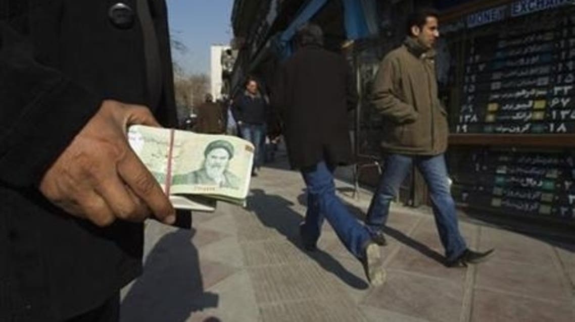 A money changer holds Iranian rial banknotes as he waits for customers in Tehran's business district January 7, 2012. (Reuters)