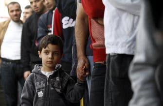 A Palestinian boy waits with a relative in a queue to buy bread in Gaza City on Nov. 17, 2012. (AFP)