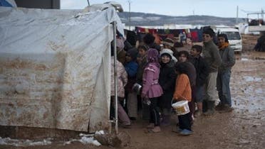 Syrian refugee children wait in freezing conditions for their families daily rations of food at a refugee camp in Bab al-Salam on the Syria-Turkey border, on Jan. 9, 2013. (AFP)
