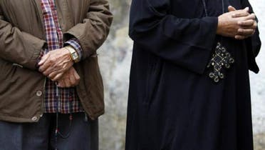 A Muslim Egyptian man holding prayer beads stands next to a Coptic Christian wearing a cross as they queue outside a polling center. (Reuters)