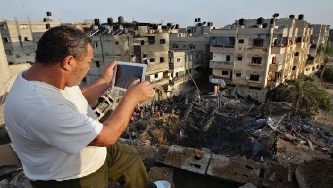 A Palestinian man uses his iPad as he takes pictures of a destroyed house after an Israeli air strike in Khan Younis in the southern Gaza Strip November 19, 2012. (Reuters)