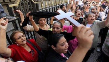 An Egyptian Coptic Christian raises a cross while others shout slogans in a demonstration last year following clashes between Muslims and Christians in Cairo. (AFP)