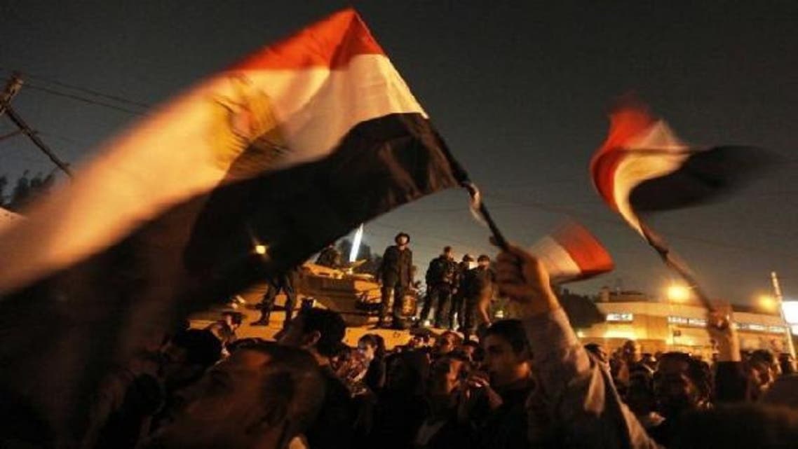 Egyptian army soldiers stand on top of a tank as protesters wave national flags outside the presidential palace. (AFP)