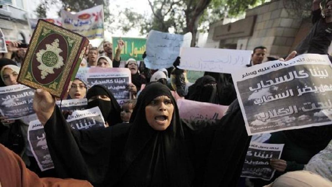 An Egyptian protester holds a copy of the Quran and a sign during a protest in front the U.S. embassy in Cairo September 11, 2012. Egyptian protesters scaled the walls of the U.S. embassy on Tuesday, tore down the American flag and burned it during a protest over what they said was a film being produced in the United States that insulted Prophet Mohammed. (Reuters)