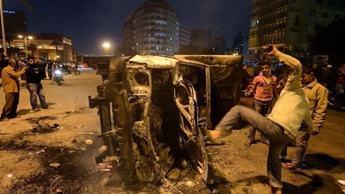 An Egyptian man gives a kick towards a police vehicle that has been burnt by angry protesters following clashes with plainclothes policemen in Cairo’s on Tahrir square on March 3, 2013. (AFP)