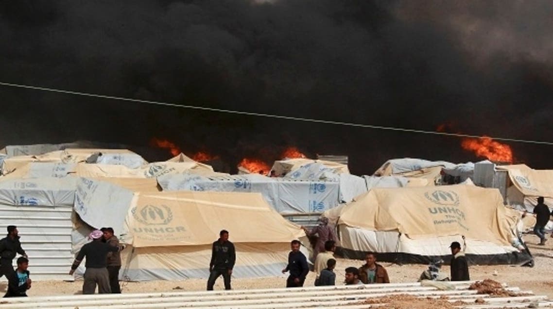 Jordanian firefighters and Syrian refugees try to remove tents before they are damaged by a fire at the Al Zaatari Syrian refugee camp in the Jordanian city of Mafraq, near the border with Syria March 8, 2013.