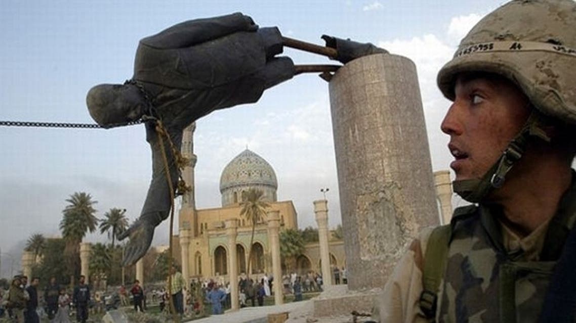 U.S. Marine watches as a statue of Iraq's President Saddam Hussein falls in central Baghdad on April 9, 2003. (Reuters)