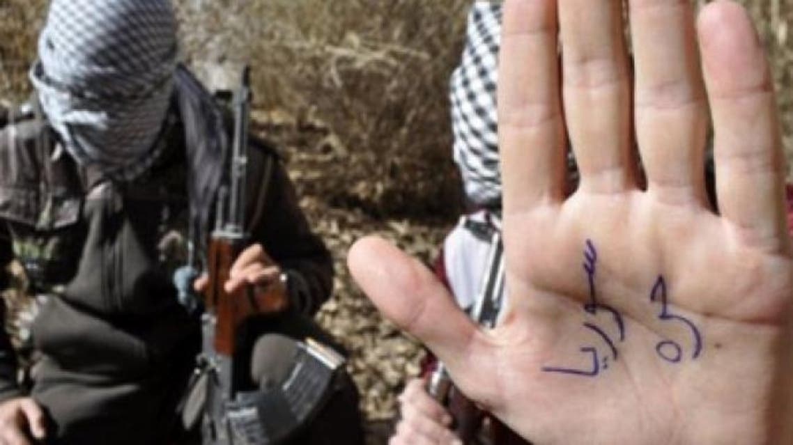 An Iraqi gunman, a member of the "Army of Free Iraqis", shows his palm reading "Free Syria" in a field in the western town of Al-Qaim close to Iraq's border with Syria (AFP Photo / Azhar Shallal)