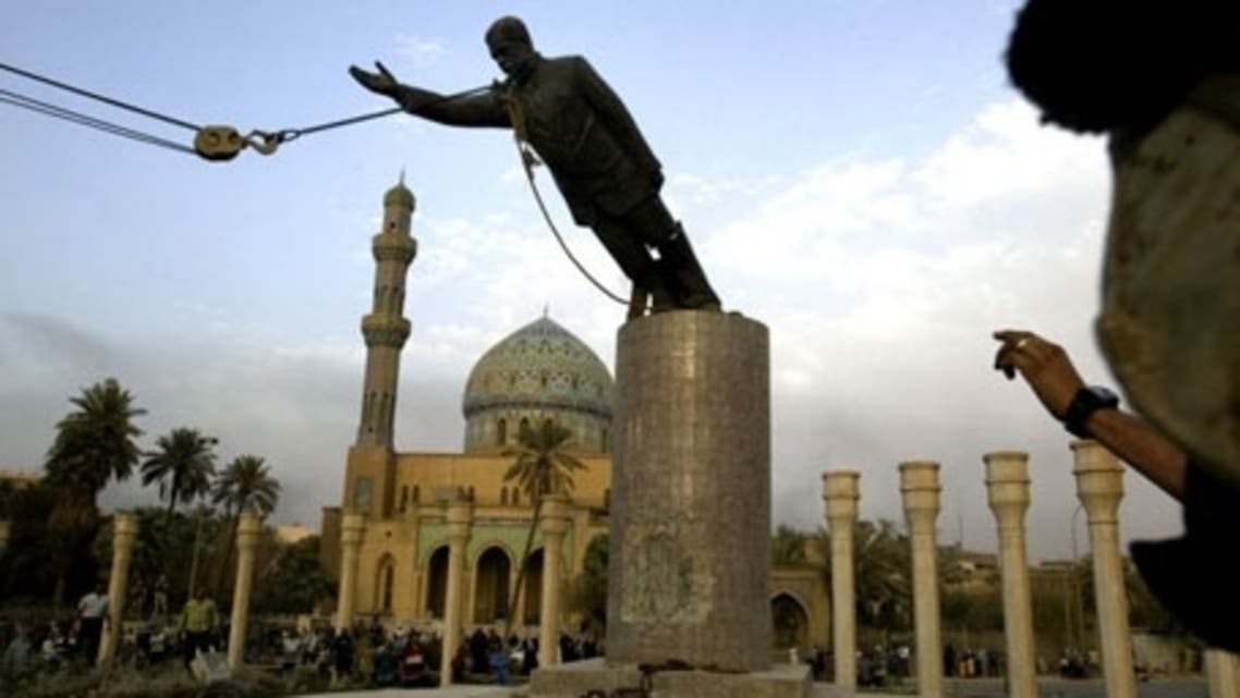 A U.S. marine watches a statue of Saddam Hussein being toppled in Baghdad on 9 April 2003. (AP)