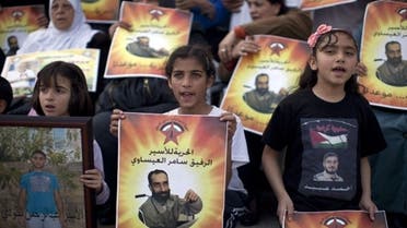 Young Palestinian protesters hold portraits of Samer Issawi, a Palestinian prisoner who has been on a hunger strike for more than 200 days, during a solidarity sit-in outside the Red Cross offices in Jerusalem on March 14, 2013. (AFP)