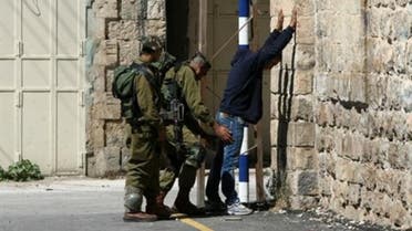 Israeli soldiers control a Palestinian man on his way to go home near the Ibrahimi Mosque and the Tomb of the Patriarch in the occupied West Bank city of Hebron on March 25, 2013. (AFP)