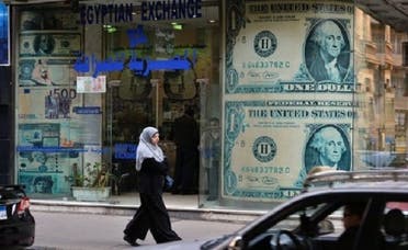 A woman walks past a foreign exchange store in Cairo on Sunday. After two years of political upheaval and weakness in the economy, companies in Egypt are struggling with a sinking currency. (AFP)