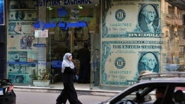 A woman walks past a foreign exchange store in Cairo on Sunday. After two years of political upheaval and weakness in the economy, companies in Egypt are struggling with a sinking currency. (AFP)
