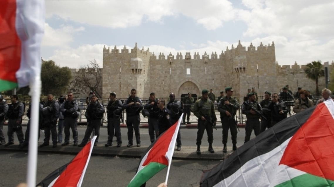 Protesters hold Palestinian flags opposite Israeli security officers standing guard before Friday prayers on Land Day outside Damascus Gate in Jerusalem’s Old City, March 30, 2012. (Reuters)