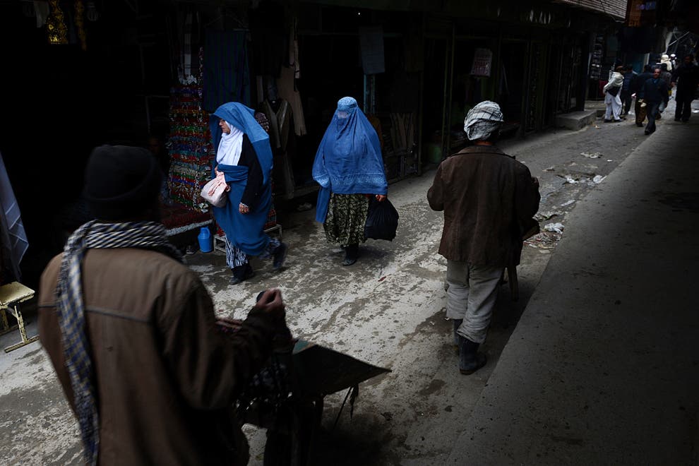 Afghan women and laborers with wheelbarrows walk down a lane in Kabul. Much of Afghanistan’s money is in an undocumented black economy. (AFP)