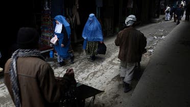 Afghan women and laborers with wheelbarrows walk down a lane in Kabul. Much of Afghanistan’s money is in an undocumented black economy. (AFP)
