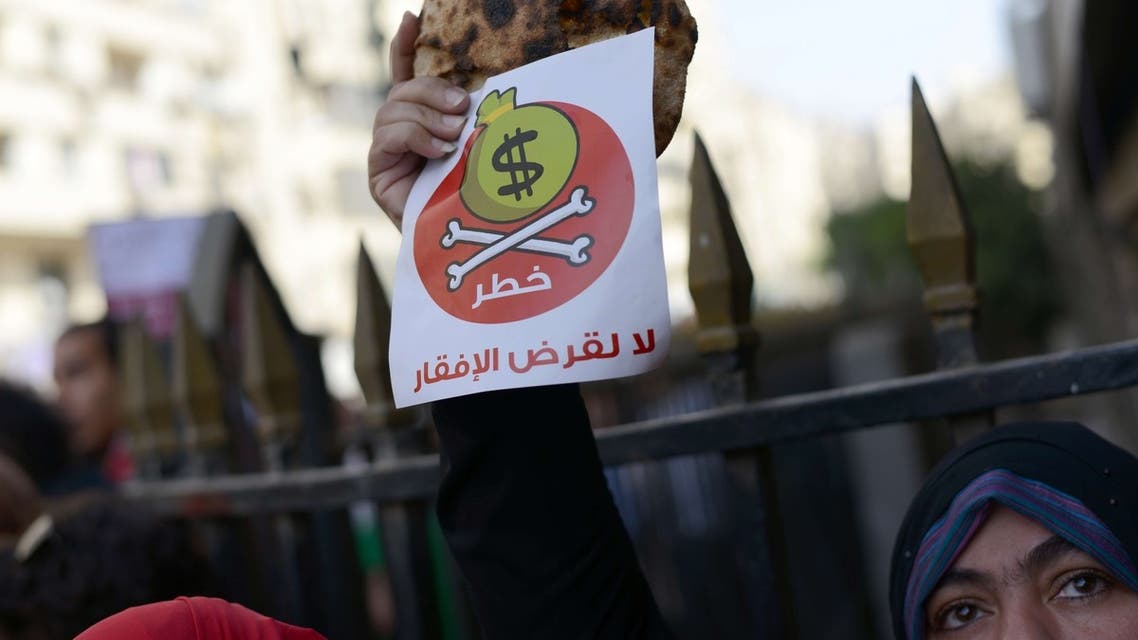 An Egyptian protester holds bread along with a flyer reading in Arabic "danger, no to loans that lead to poverty". (AFP)