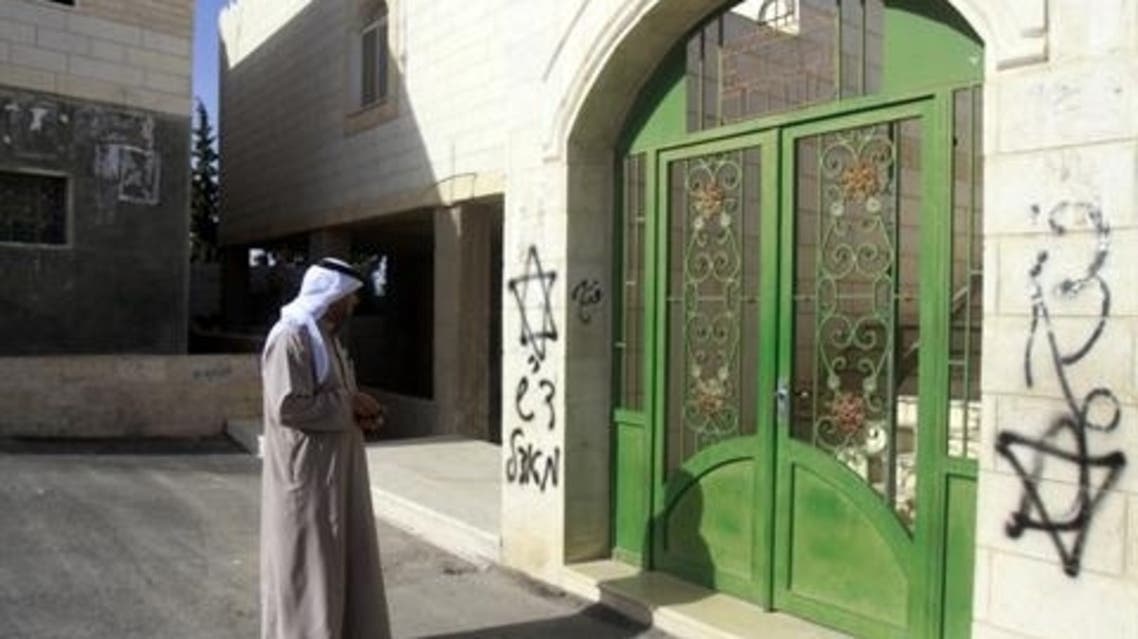 A Palestinian looks at Hebrew grafittis sprayed on the walls of a mosque on April 7, 2013 in the West Bank village of Tuqua