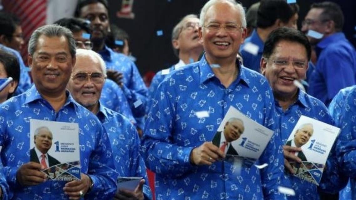 Malaysian PM Najib Razak (2R) smiles as he holds a copy of his coalition's election manifesto with other members party ahead of upcoming polls in Bukit Jalil, Kuala Lumpur, in this April 6, 2013 file photo. (AFP)