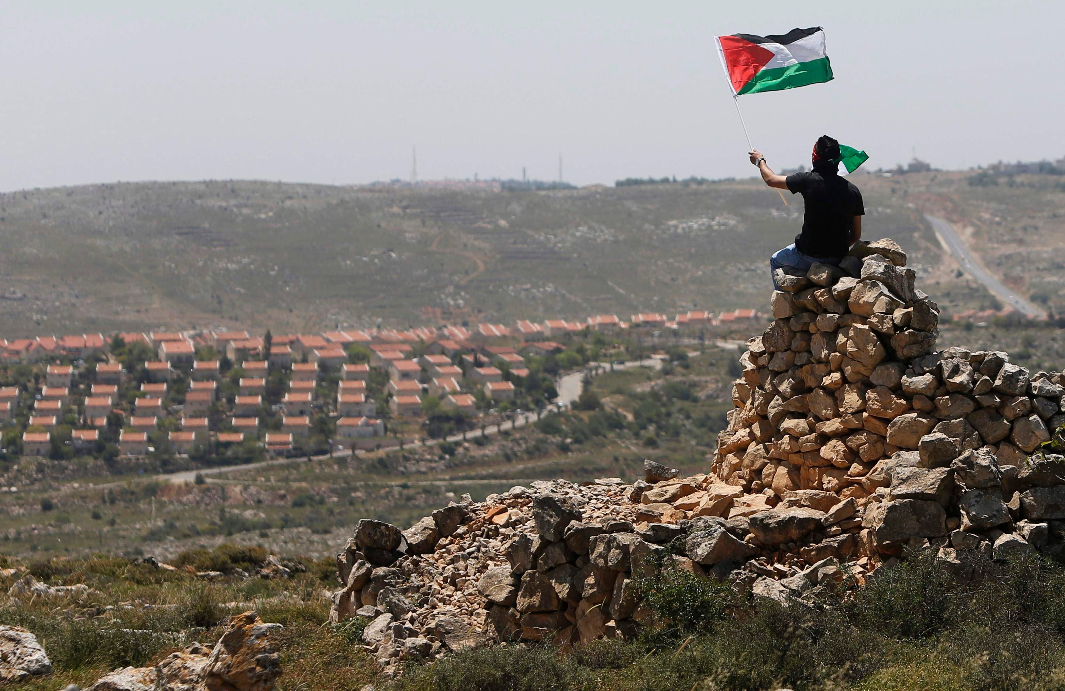 A protester waves a Palestinian flag in front of the Jewish settlement of Ofra during clashes near the West Bank village of Deir Jarir near Ramallah April 26, 2013. (Reuters)