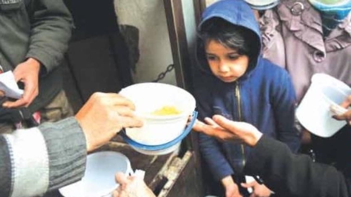 Syrians wait to receive a meal in the Bustan Al-Qasr district of the northern city of Aleppo. (AFP)