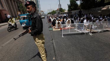 A policeman stands guard where men participate in Friday prayers, near a mosque, along a road in Karachi May 17, 2013. (Reuters)