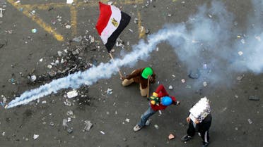 A protester throws a tear gas canister, which was earlier thrown by riot police, as another protester waves the Egyptian flag at Tahrir Square in Cairo November 21, 2011. (Reuters)