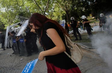 A demonstrator covers her face as riot police use tear gas to disperse the crowd during a protest against the destruction of trees in a park brought about by a pedestrian project, in Taksim Square in central Istanbul May 31, 2013. (Reuters)