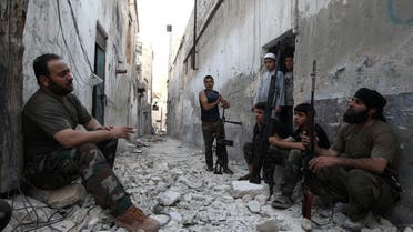 Members of the Free Syrian Army talk as they sit with their weapons in a damaged street in Aleppo's Karm al-Jabal district, June 3, 2013. Reuters