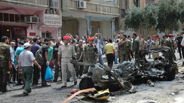People look at the wreckage of a vehicle after a suicide car bomb exploded in the al-Adaweya district of Homs June 8, 2013 REUTERS