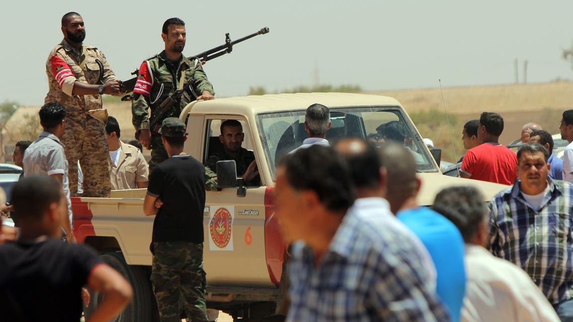 Libyan security personnel stand guard in an armed pick-up as residents of the eastern Libyan city of Benghazi bury the bodies of the demonstrators AFP
