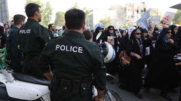 Iranian police watch as female supporters of Iranian presidential candidate and lead nuclear negotiator Saeed Jalili hold up his image during a campaign rally along Valiasr Street in the Iranian capital Tehran, on June 9, 2013. (AFP)