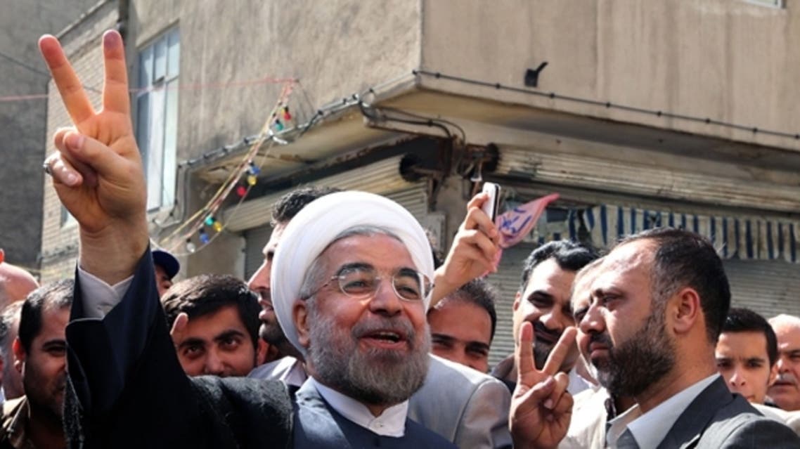 Iranian moderate presidential candidate, Hassan Rowhani (C) flashes the sign of victory as he leaves a polling station after voting on in Tehran during the first round of the presidential candidate. (AFP)
