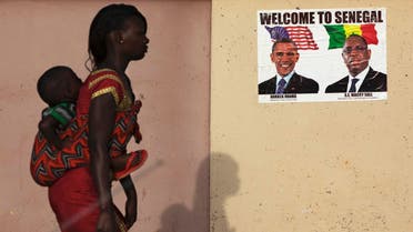 A woman carrying her baby on her back walks past a poster of U.S. President Barack Obama and Senegal's President Macky Sall before Obama's visit in Dakar June 26, 2013. (File photo: Reuters)