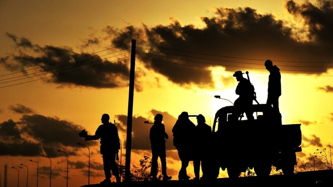 Libyan rebel fighters are silhouetted at sunset on March 7, 2011 in the oil center of Brega. AFP