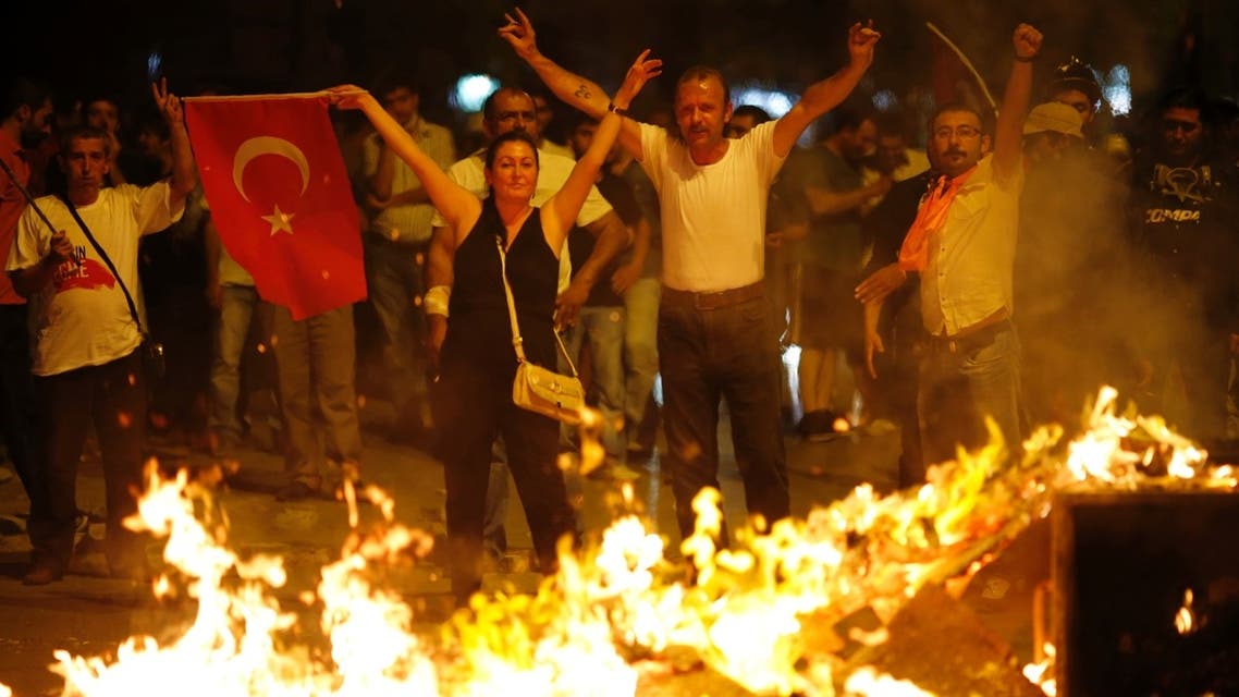 Anti-government protesters make V-signs and wave a flag as they block a road during a demonstration in Ankara early June 26, 2013. REUTERS