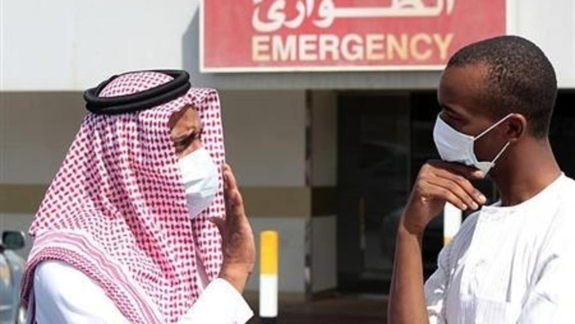 Men wearing surgical masks as a precautionary measure against the novel coronavirus, speak at a hospital in Khobar city in Dammam May 23, 2013.