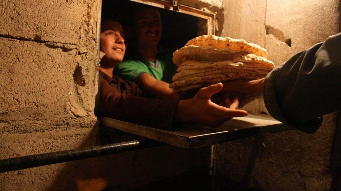 Syrian men line up to buy bread at the only bakery still open in the city of Al-Bueda. (AFP)