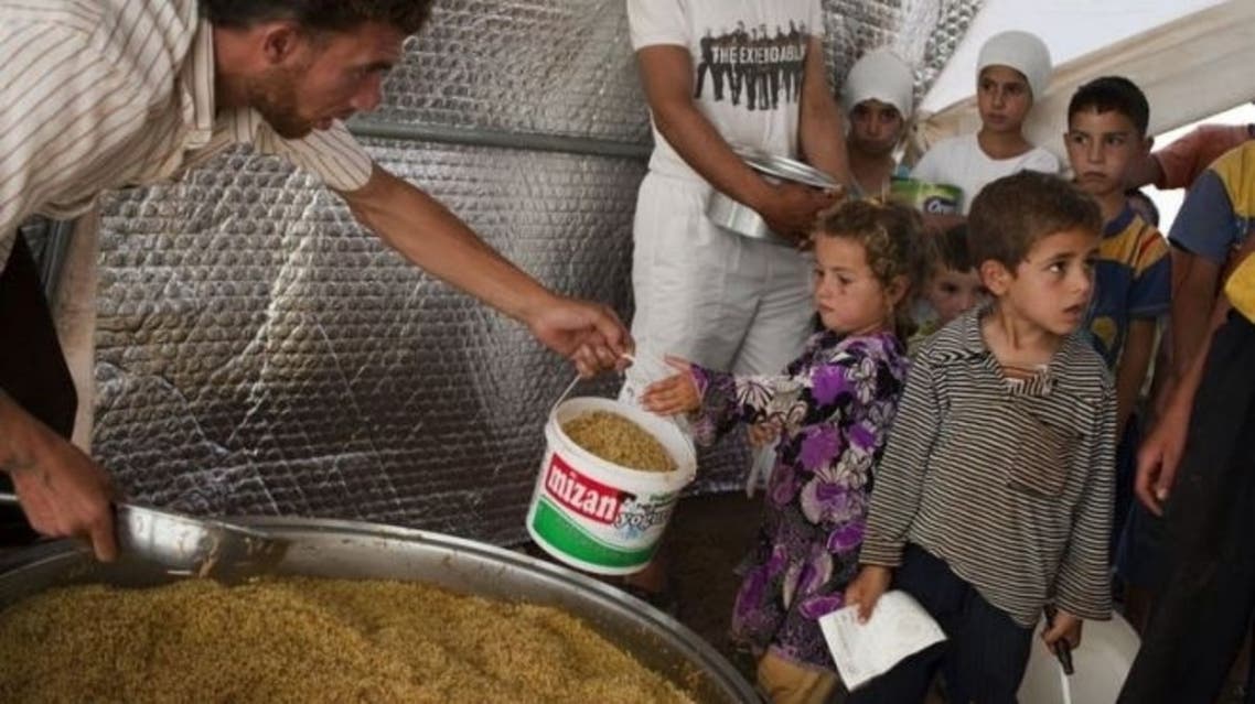 A volunteer shares out food to the people in the Bab al-Salam refugee camp for displaced Syrians near the border with Turkey on July 2, 2013. (AFP)