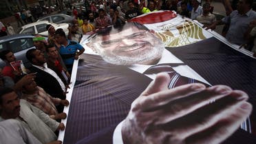 Ousted President Mohamed Morsi supporters and Muslim Brotherhood members hold a giant portrait of him as they demonstrate against his toppling at Raba al-Adwyia mosque on July 7, 2013 in Cairo. AFP