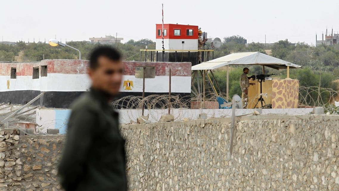 A Hamas policeman (L) stands in Rafah in the southern Gaza Strip on the border with Egypt, on July 8, 2013, while Egyptian soldiers standing on top of a watch-tower keeps watch from the Egyptian side of the border. AFP