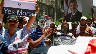 Supporters of Muslim Brotherhood and Egypt's ousted president Mohammad Mursi (on posters) raise up placards and deploy a giant national flag during a rally on the road leading to the government headquarters on July 17, 2013. (Reuters)